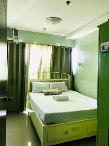 卡加延德奧羅的住宿－Primavera Residence Silver 3Kates，一间卧室配有一张带绿色窗帘的大床