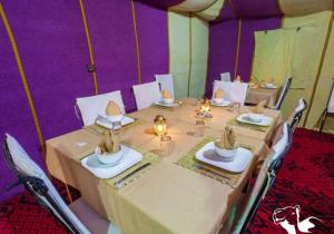a dining table in a tent with purple walls at Sunshine luxury tent in Merzouga