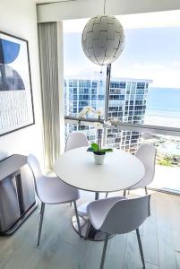 - une table et des chaises blanches dans une chambre dotée d'une grande fenêtre dans l'établissement Luxury Beach-Front High-Rise Apartment, à San Diego