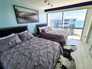 a bedroom with two beds and a large window at Luxury Beach-Front High-Rise Apartment in San Diego