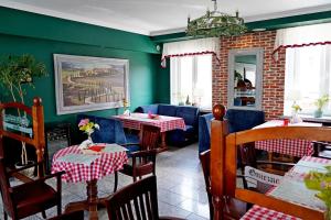 a restaurant with two tables and chairs and green walls at Hotel Adalbertus in Gniezno