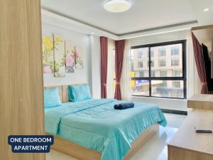 1 dormitorio con cama con sábanas azules y ventana en WH Chamkarmon Residence en Phnom Penh