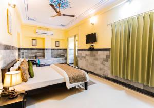 Kalyan Villa Homestay في أودايبور: غرفة نوم بسرير وتلفزيون على جدار