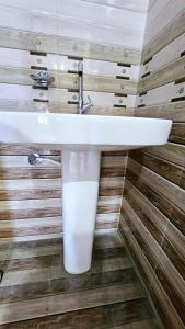 baño con lavabo blanco en una pared de madera en Gopal Hotel and Palace, en Jhunjhunūn