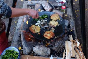a person cooking food in a pan on a grill at Naawa Nature Camp in Korppoo