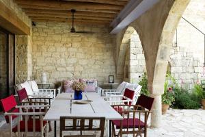 a table and chairs in a room with a stone wall at Modus Vivendi Holidays Arsos in Arsos