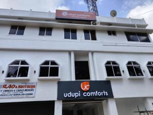a white building with a sign in front of it at Udupi Comforts in Udupi