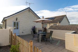 a patio with a table and an umbrella at St Helens Apartment 1 - Short Walk to Beach in Amroth