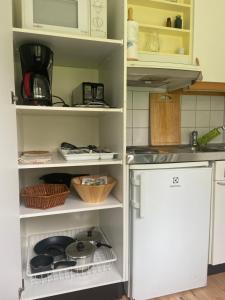 cocina con estanterías blancas y nevera blanca en Åvillan - River house, en Lagan