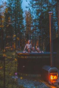 a group of people in a hot tub in the woods at Villa ArcticFox Levi in Kittilä