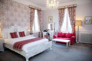 a bedroom with a white bed and a red couch at Shendish Manor Hotel & Golf Course in Hemel Hempstead