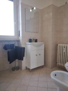 La salle de bains est pourvue d'un lavabo blanc et d'un miroir. dans l'établissement Spazioso appartamento Parabiago, à Parabiago