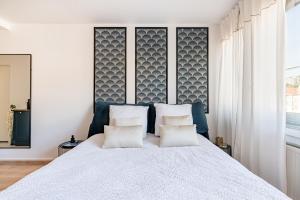 1 dormitorio con 1 cama blanca grande y 2 almohadas en SARAH - Design Studio Lumineux Bergson, en Saint-Étienne