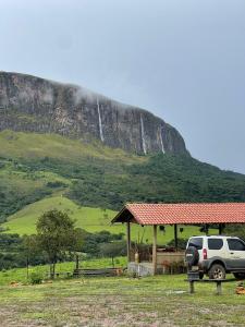 - un suv garé à côté d'un kiosque avec une montagne dans l'établissement Pousada Vale da Canastra, à São José do Barreiro