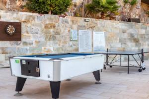 una mesa de ping pong frente a una pared de piedra en Club Cala Blanca, en Taurito
