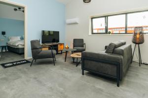 ein Wohnzimmer mit einem Sofa, Stühlen und einem TV in der Unterkunft Duikresort Sub Ocean Hotel in Oud-Vossemeer