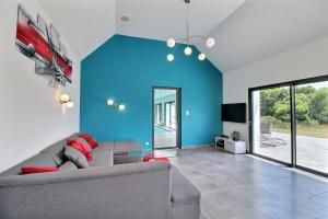 een woonkamer met een bank en een blauwe muur bij Longère avec piscine intérieure, spa, sauna in Douarnenez