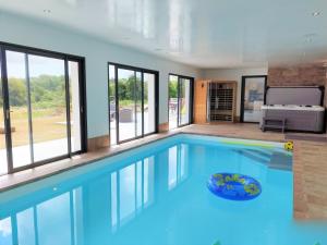 een groot zwembad met blauw water in een kamer met ramen bij Longère avec piscine intérieure, spa, sauna in Douarnenez