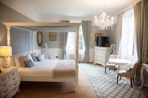 ein Schlafzimmer mit einem Himmelbett und einem Schreibtisch in der Unterkunft Shendish Manor Hotel in Hemel Hempstead