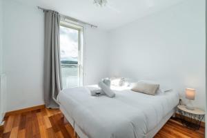 ein weißes Bett in einem Zimmer mit einem großen Fenster in der Unterkunft Le Duplex Paris Seine Free Parking Terrasse in Issy-les-Moulineaux