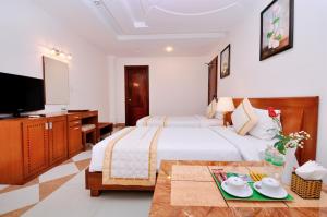 a hotel room with a bed and a flat screen tv at Tan Hoang Long Hotel in Ho Chi Minh City