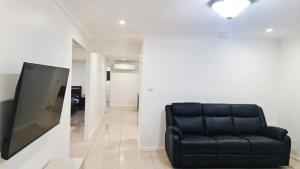 a black couch sitting in a living room with a tv at 3 Bed Room, Luxury Home in Schofields