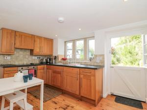 a kitchen with wooden cabinets and a white table at Abbey Cottage Montacute in Montacute