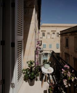 a balcony with potted plants and a table on it at Architect’s home pad - Valletta in Valletta