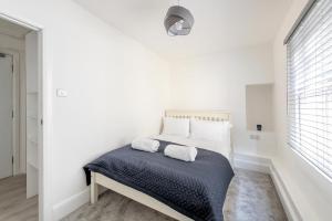 Flat in Bath City Centre في باث: غرفة نوم بيضاء مع سرير عليه منشفتين