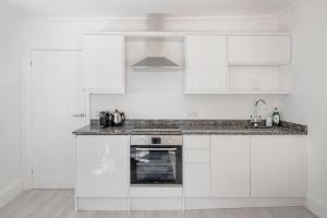 una cocina blanca con armarios blancos y fregadero en Flat in Bath City Centre, en Bath