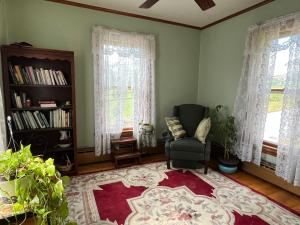uma sala de estar com uma cadeira e janelas em Cheney House Bed & Breakfast em Ashland