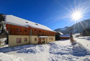a building in the snow with the sun behind it at JUFA Hotel Donnersbachwald in Donnersbachwald