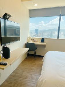 台北市にある小隱居Hermit Dorm-聖雄商旅のベッドと机、テレビが備わったホテルの部屋