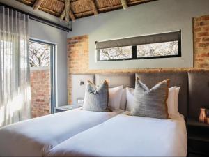 1 Schlafzimmer mit 2 weißen Betten und einem Fenster in der Unterkunft NAKO Safari Lodge in Dinokeng Game Reserve