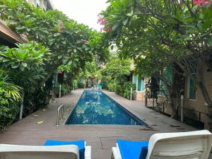 een zwembad in een tuin met bomen en stoelen bij BBHOUSE pattaya in Pattaya South