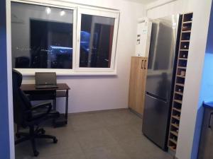 a office with a desk and a refrigerator and a table with a laptop at Hightower Apartment in Floreşti
