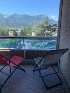 2 Stühle auf einem Balkon mit Bergblick in der Unterkunft Appartement au plan d'eau - chez Laurence in Embrun