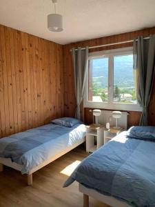 1 Schlafzimmer mit 2 Betten und einem großen Fenster in der Unterkunft Appartement au plan d'eau - chez Laurence in Embrun