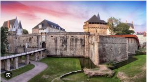 um velho castelo com um jardim relvado à frente dele em La Grande Madeleine em Nantes