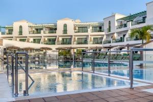 un hotel con piscina frente a un edificio en Club del Carmen en Puerto del Carmen