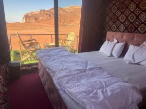 a bed in a room with a view of the desert at Wadi Rum Desert Goals camp in Wadi Rum