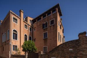 un viejo edificio de ladrillo con un árbol delante de él en Santa Croce Design Apartment R&R, en Venecia