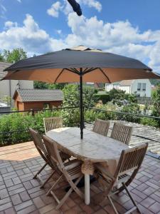 einen Tisch und Stühle mit Sonnenschirm auf einer Terrasse in der Unterkunft Le Cerisier - Charmante maison dans le vignoble in Sigolsheim