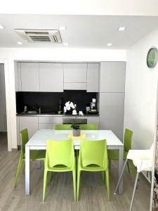 Green House Varazze في فاراتسي: غرفة طعام مع طاولة بيضاء وكراسي خضراء