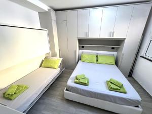 2 bedden in een kleine kamer met groene kussens bij Green House Varazze in Varazze