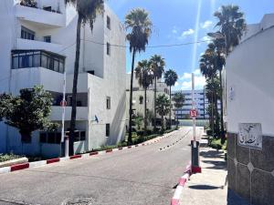 una calle vacía frente a un edificio con palmeras en 2 bedrooms + living room. Intelak 1 Rabat Agdal en Rabat