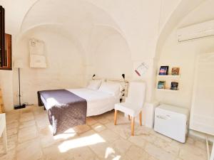 a bedroom with a white bed and a white chair at Parco della Vigna in Martina Franca