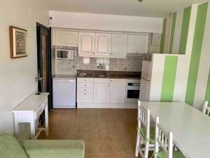 a kitchen with white cabinets and green and white stripes at Apartament a L’Estartit x 4 in Torroella de Montgrí