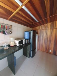 a kitchen with a counter with a microwave and a refrigerator at Chalé em Maragogi in Maragogi