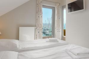 - une chambre avec un grand lit blanc et une fenêtre dans l'établissement Yachthafenblick, à Heiligenhafen